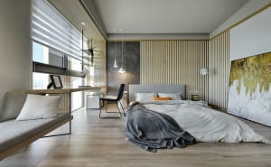 A modern minimalist bedroom with wood paneling, featuring a gray upholstered bed and a large abstract painting.