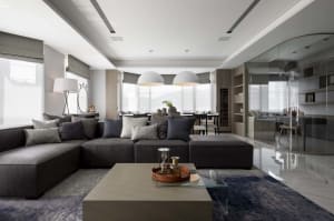 Modern living room featuring a comfortable fabric sofa adorned with various colored pillows, a glass coffee table, and a slee