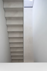 Modern concrete stairs with white walls and a skylight.