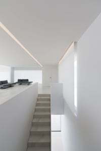 Modern minimalist staircase with white walls and concrete steps.