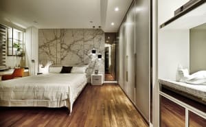 Modern minimalist bedroom with a marble accent wall and wooden flooring.