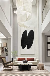 A modern white marble lobby with a white fabric sculpture and black abstract art hanging from the ceiling, white leather couc