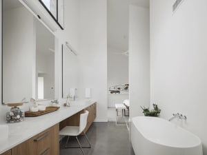 Modern minimalist bathroom with white walls, a white bathtub, and a sleek wooden vanity.