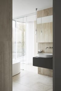 Modern minimalist bathroom with stone surfaces and a white bathtub.