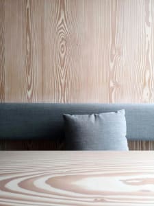 A minimalist bedroom with a wooden headboard and matching headboard cover, showcasing sleek and modern design.