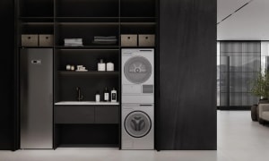 A minimalist laundry room featuring black steel appliances, open shelving, and foldable storage boxes.