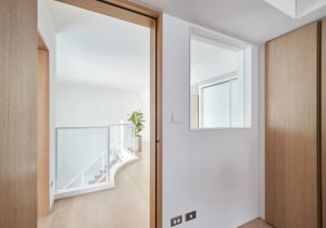 A modern residential interior featuring a sleek, white concrete staircase with a transparent glass railing.
