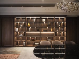 Luxurious living room with wooden shelves displaying various decorative items and lighting focused on the shelves.