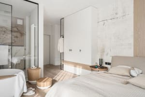 A modern minimalist bedroom with light wood flooring, marble countertops, and white walls.