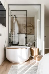 Modern minimalist bathroom with marble walls and a circular bathtub.