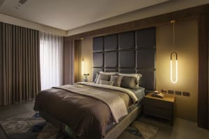 Modern bedroom featuring a fabric and leather upholstered bed against a contemporary wooden headboard and decorative pendant 