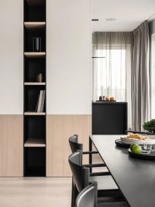 A modern dining room featuring minimalist furniture, sleek black and light wood finishes, and a long black dining table surro