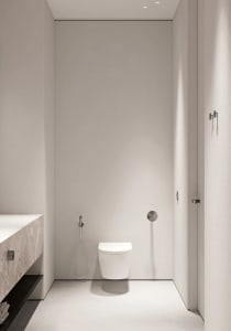 A minimalist white bathroom with a toilet and hand shower.