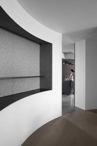 Modern minimalist kitchen with concrete walls, wooden flooring, and metallic accents
