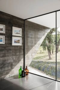 Interior design featuring minimalist concrete walls and windows with a view of nature.