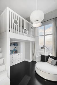 A modern bathroom featuring white concrete walls and floors, with a circular white bathtub and a white vanity cabinet.