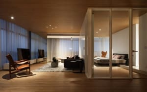 Modern minimalist living room featuring wood-paneled walls and floor-to-ceiling windows with sheer curtains.