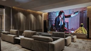 Modern, comfortable seating in a home theater with a large screen displaying a movie scene.