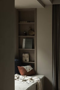 A modern bookshelf featuring decorative items and a cozy bench seat.