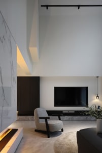 A modern living room featuring a concrete floor, minimalist design, and a single armchair in front of a television.