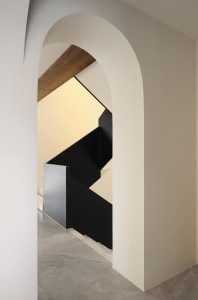Modern minimalist interior with black staircase and metallic railings.