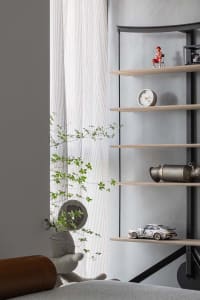 A minimalist shelf decorated with a small figurine, a round clock, a white toy car, and a metallic object.