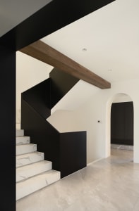 Modern staircase with black railings and marble steps.