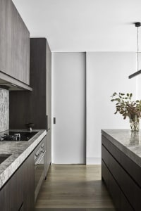 Modern minimalist kitchen with concrete countertops and wooden flooring.
