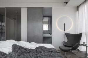 A minimalist bedroom featuring a concrete wall and a circular light fixture.