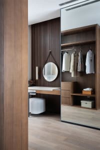 Modern minimalist closet with wooden storage system, storage bins, and clothing hanging and displayed.