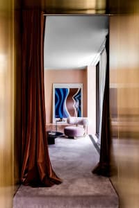 Modern interior space with velvet curtains, marble flooring, and contemporary artwork.