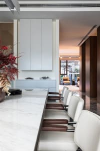 Modern kitchen interior with white marble countertops and chairs.