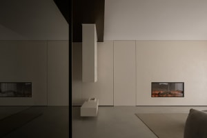 A minimalist living room with concrete walls and an electric fireplace.
