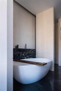 A minimalist bathroom with a free-standing bathtub, marble tiles, and concrete accents.