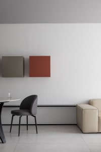 Modern minimalist living room with a beige sofa, a black dining chair, and geometric wall art.