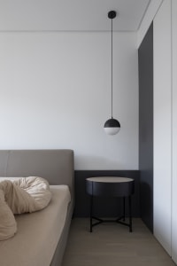 Minimalist bedroom with a bed, a bedside table, and a matte black pendant light hanging from the ceiling.