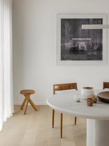 Modern dining room featuring a round marble table and wooden chairs.