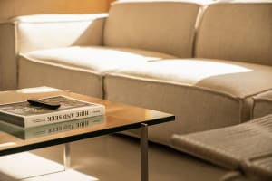 A modern living room featuring comfortable cushions arranged on a beige sofa and chair, with a coffee table displaying a book