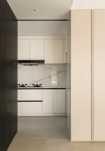 A modern minimalist kitchen with a white marble countertop and white cabinets.