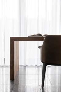 A minimalist office desk made of wood with a leather chair.