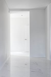 A minimalist, modern interior featuring a marble flooring and white walls.