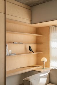 A modern residential shelving space featuring wooden shelves with decorative objects and a sleek desk lamp.