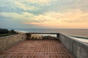Concrete terrace overlooking the sea with red brick tiles on the floor.