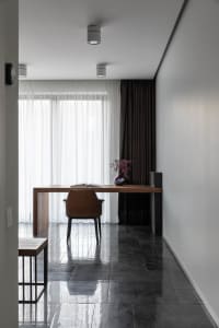 A minimalist home office with a wooden desk, glass panels, and a leather chair.