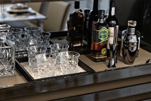 A sleek, modern bar counter featuring polished glass and ceramic materials, with various bottles and glasses neatly arranged.