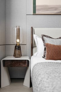 Modern minimalist bedroom with a bed, pillows, a table lamp, and a framed picture on the wall.