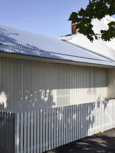 Modern building exterior with corrugated metal roof and white, vertical siding.