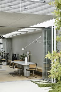 Modern minimalist dining room featuring sleek, contemporary furniture with a concrete table and wooden chairs.