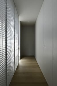 A minimalist interior space featuring wooden flooring and white walls and cabinets.