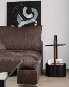A modern living room featuring a fabric sofa, abstract artwork, and a side table.